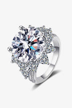 Flower-shaped silver ring with a large round Carat Moissanite center stone and smaller triangular accent stones in a polished setting