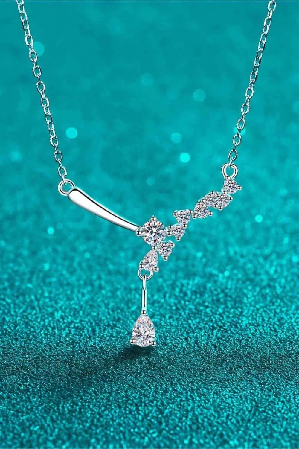 925 sterling silver necklace with sparkling clear Carat Moissanite stones arranged in a unique asymmetric design with a dangling teardrop gem.