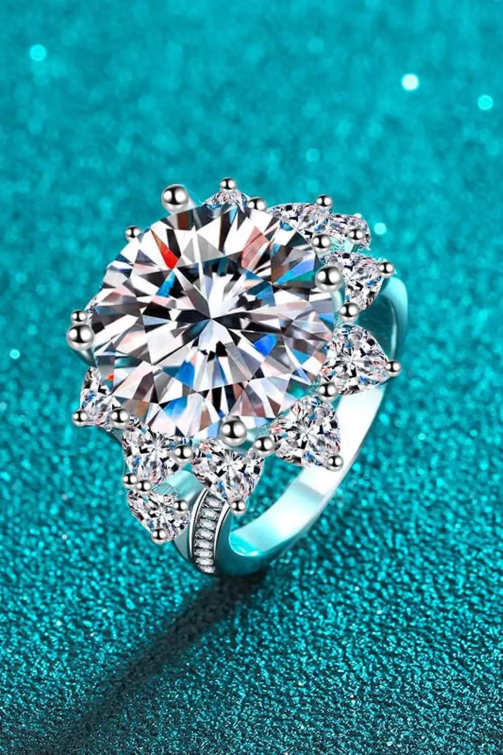 Flower-shaped silver ring with a large central sparkling Carat Moissanite stone surrounded by smaller clear stones in a modern design