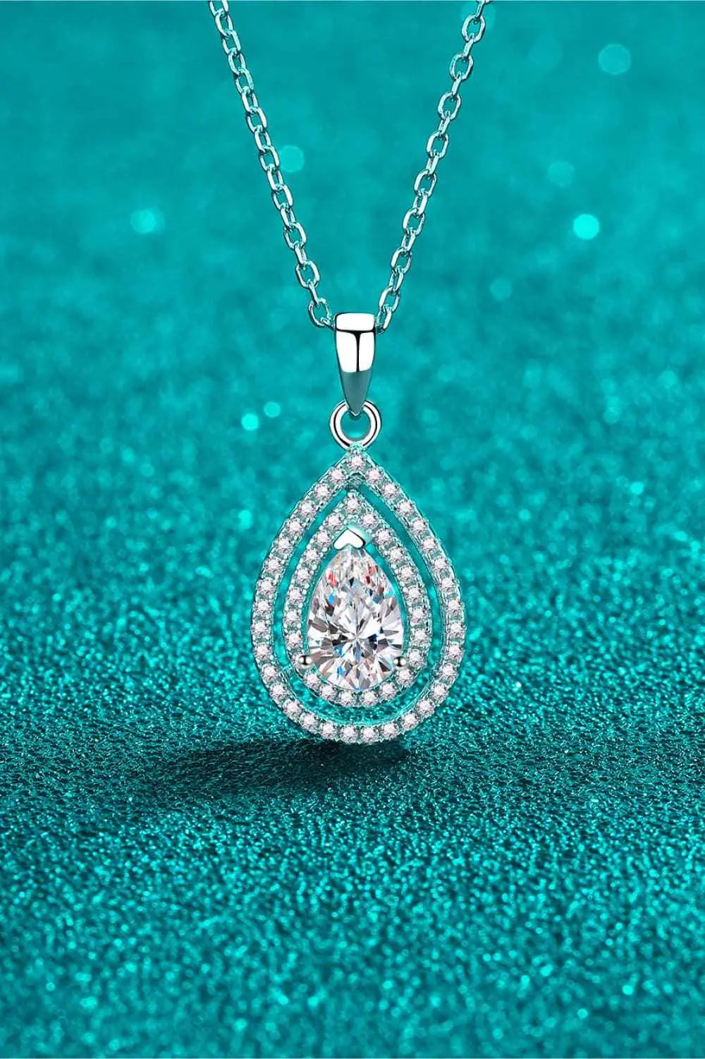 Carat Moissanite Teardrop Pendant necklace with a 1 carat pear-shaped moissanite center stone surrounded by smaller accent stones on a silver chain
