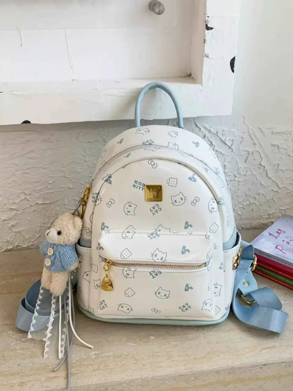 Mini white Cartoon Pattern Backpack with blue straps, cute cat and bone prints, and a bear pendant keychain