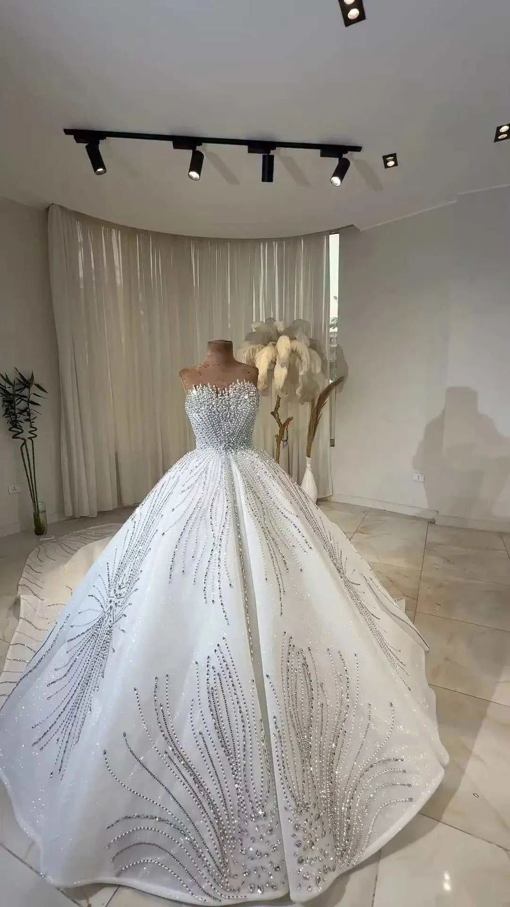 Celeste Crystal Ball Gown featuring a white off-the-shoulder silhouette with intricate silver beading and lace detail on a floor-length skirt