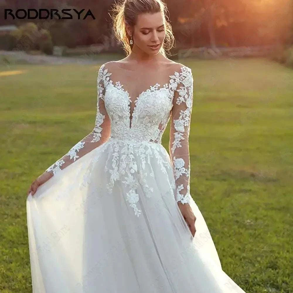 Customized Wedding Dress featuring long sheer lace sleeves, illusion floral applique bodice, scoop neckline, and flowing white tulle a-line skirt