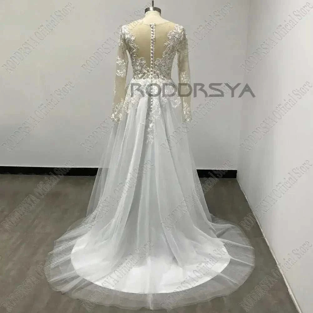 Customized Wedding Dress featuring long sheer sleeves, illusion back with buttons, lace applique bodice, and flowing tulle A-line skirt