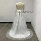 Customized Wedding Dress featuring long sheer sleeves, illusion back with buttons, lace applique bodice, and flowing tulle A-line skirt