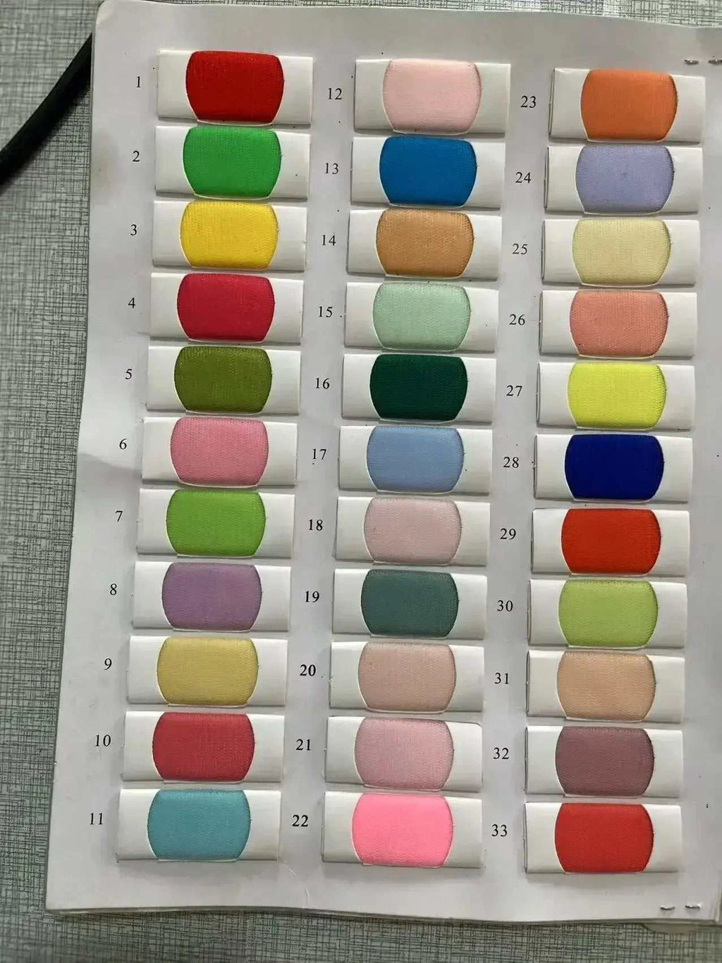 Fabric color swatches in shades of red, green, yellow, blue, pink, purple, and brown arranged in rows with white backing cards for Customized Wedding Dresses.