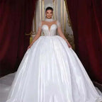 White lustrous satin ball gown wedding dress with full long sheer sleeves adorned with pearls and a high neckline