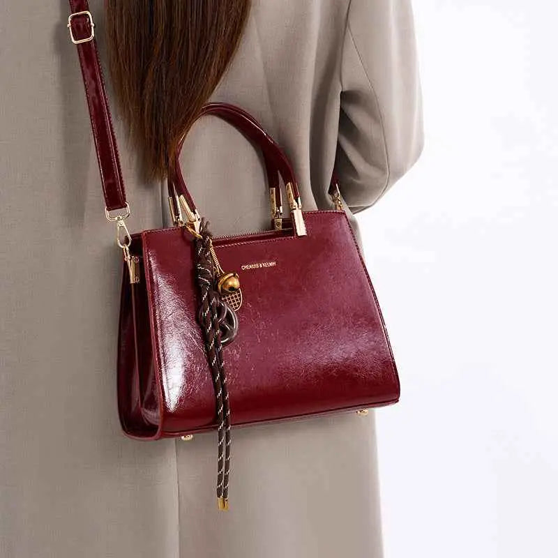 Detachable Strap Crossbody Bag in shiny burgundy PU leather with gold hardware and decorative braided tassel charm