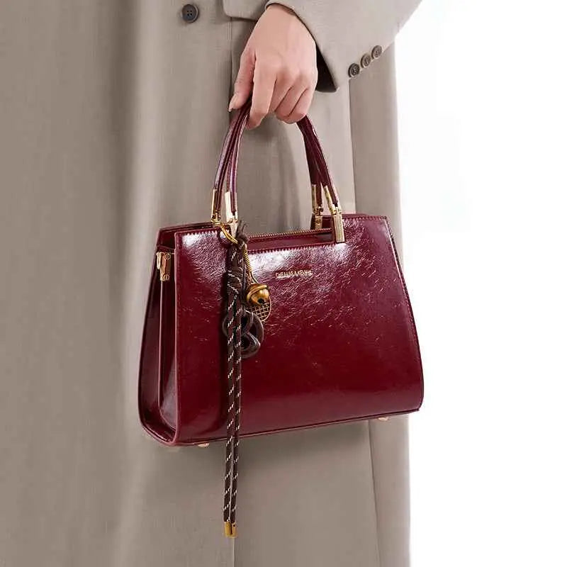 Detachable Strap Crossbody Bag in glossy burgundy PU leather with gold hardware and braided strap detail carried by hand