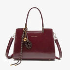 Detachable Strap Crossbody Bag in glossy dark red PU leather with top handles, gold hardware, and decorative hanging charms