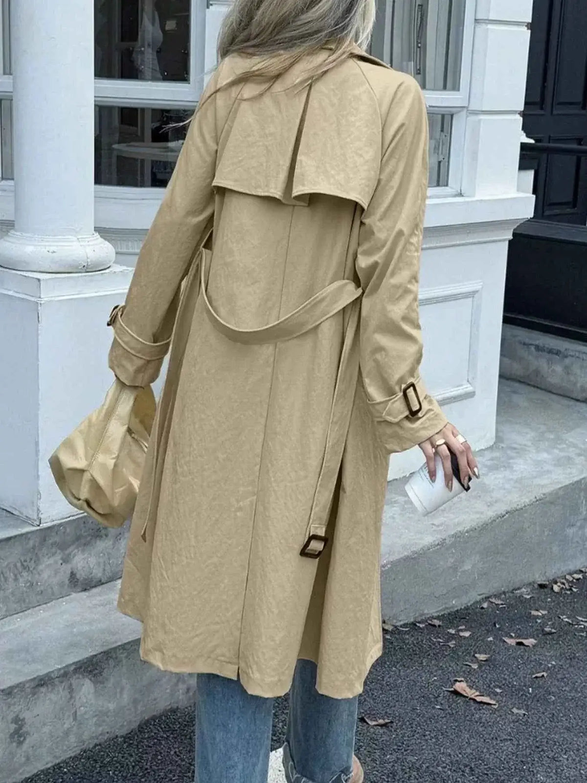 Double-Breasted Belted Trench Coat in beige polyester featuring buttoned cuffs and a rear storm flap detailing