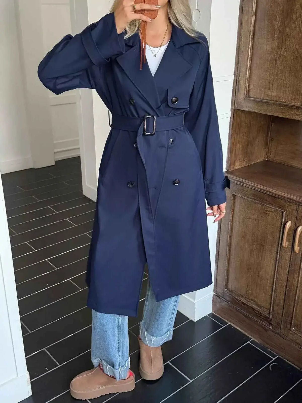 Double-Breasted Belted Trench Coat in navy blue polyester with buttoned front and belted waist worn over jeans