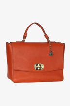 Elegant Handbag in orange vegetable tanned leather with gold metal closure, short handle, and decorative charm