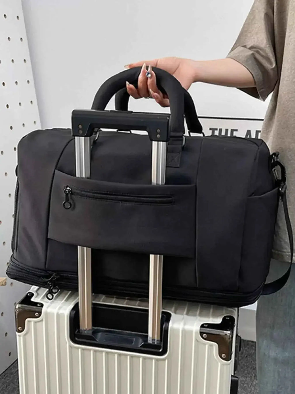 Expandable Rolling Duffel Bag in black Oxford cloth with top handles, front zipper pocket, and detachable shoulder strap