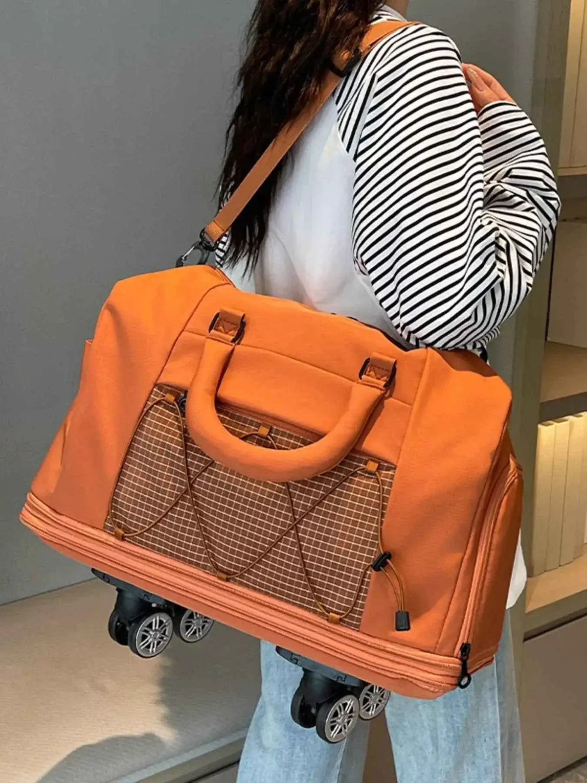 Expandable Rolling Duffel Bag in orange Oxford cloth with brown checkered front pocket and four black wheels