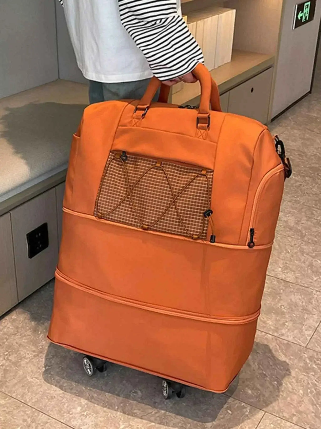 Expandable Rolling Duffel Bag in orange Oxford cloth with front zip pocket and four wheels for easy mobility