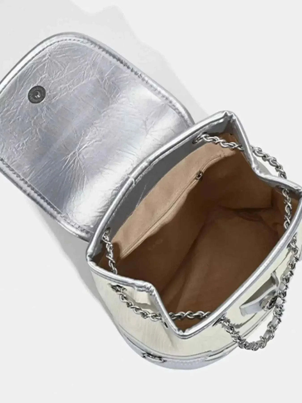 Heart Flap Backpack in metallic silver PU leather with chain straps and beige fabric interior lining visible inside the bag.