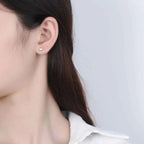 Heart-Shaped Stud Earrings in silver with sparkling zircon stones worn on ear, delicate and small size design