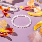 Ice Quartz bracelet with translucent 6mm crackled beads on a pastel surface surrounded by orange and yellow flower petals and crystals