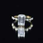 IGI Certified 4 Carat emerald cut diamond engagement ring with spaced round accent stones on a gold band