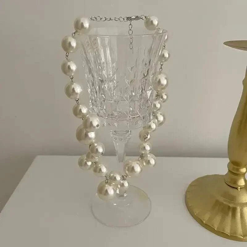 Imitation Pearl Women's Necklace featuring large round white simulated pearls with silver chain links, displayed on a clear glass