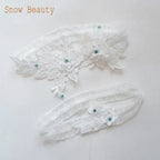 White wedding garter belt set with floral lace applique and small blue crystals, delicate and romantic design