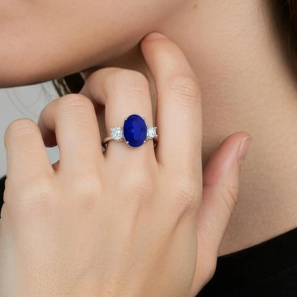 Lab-Grown Blue Sapphire ring with deep blue oval center stone, flanked by round diamonds set in polished white gold band