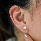 Round brilliant lab-grown diamond earrings set in yellow gold with secure four-prong setting and push-back closure worn on ear