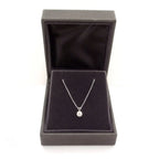 Lab grown diamond pendant with a round cut clear stone set in silver prong setting on a delicate silver chain inside a grey velvet jewelry box