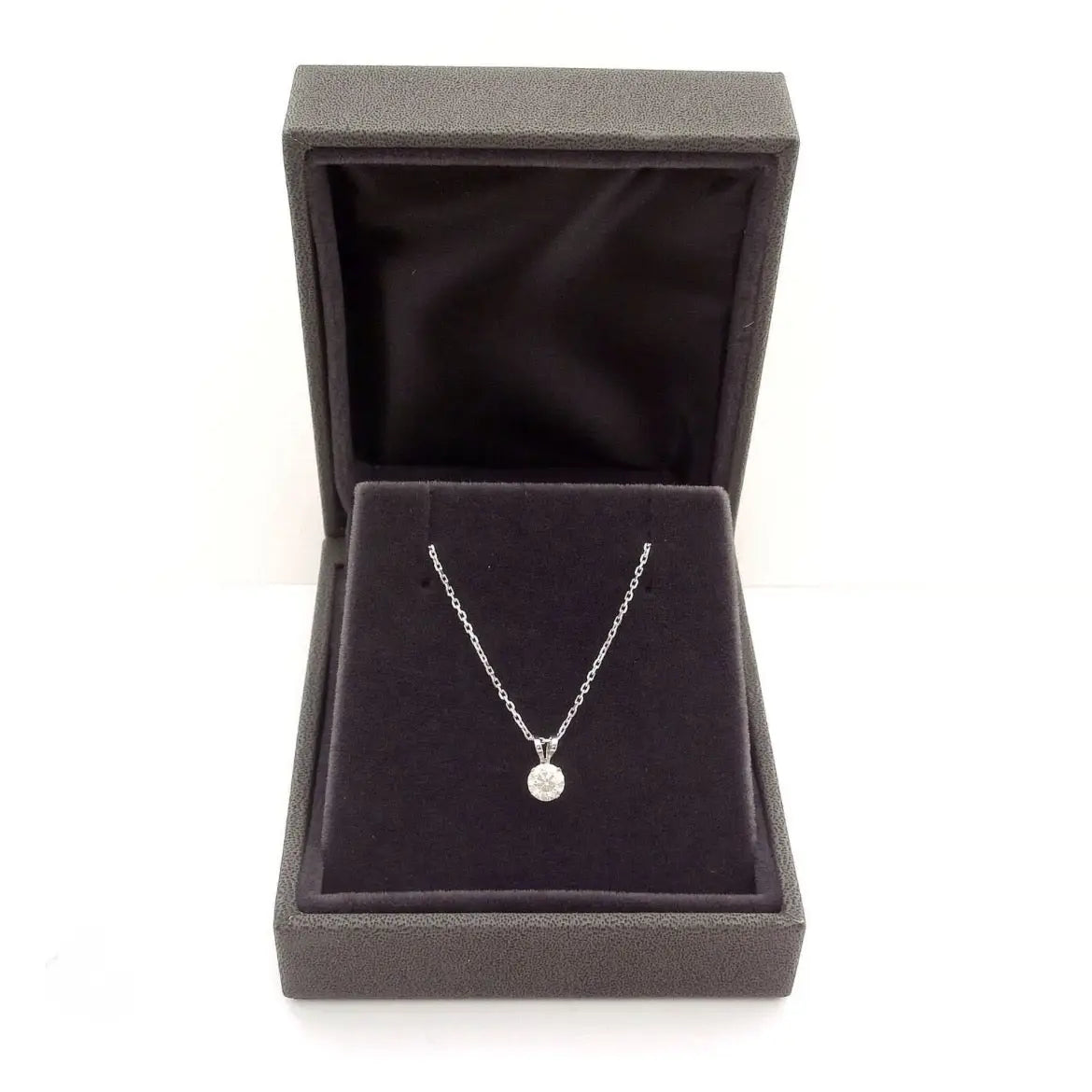 Lab grown diamond pendant with a round cut clear stone set in silver prong setting on a delicate silver chain inside a grey velvet jewelry box