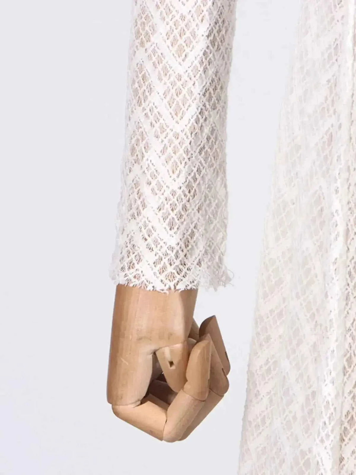 Lace Mock Neck long sleeve maxi dress in white lace fabric with diamond pattern on a mannequin hand