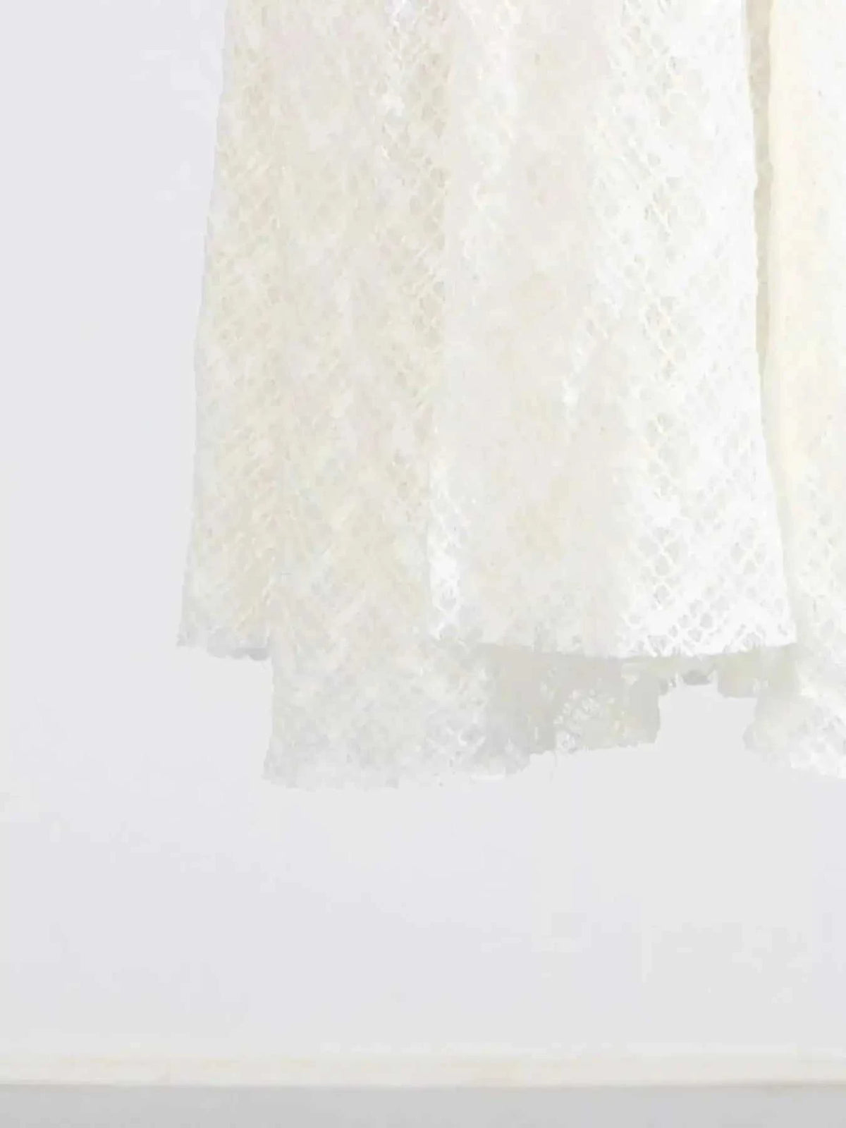 White lace maxi dress hem with delicate floral pattern detail and lined polyester fabric visible on bottom edge