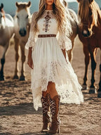 Lace Trimmed High-Low Dress in cream with intricate lace detailing, cutout front, bell sleeves, and asymmetrical hem paired with brown lace-up boots.