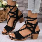 Black suede Lace-Up Block Heel Sandals with wooden block heels, open toe, and ankle strap laces on a model's feet.