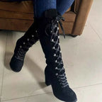 Black suede lace up block heels boots with high heels, metal eyelets, and front lacing detail.