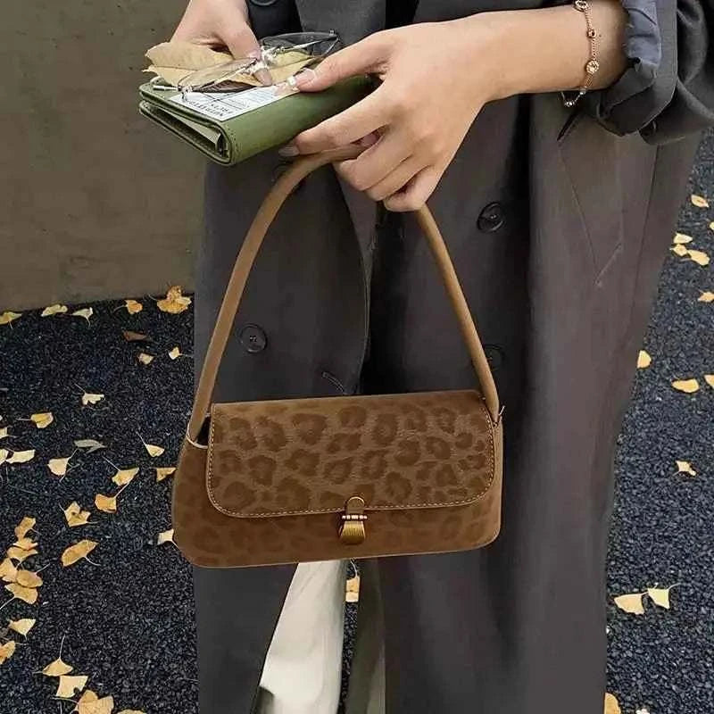 Leopard Print Shoulder Bag in brown suede with a small rectangular shape and a single shoulder strap held by a person