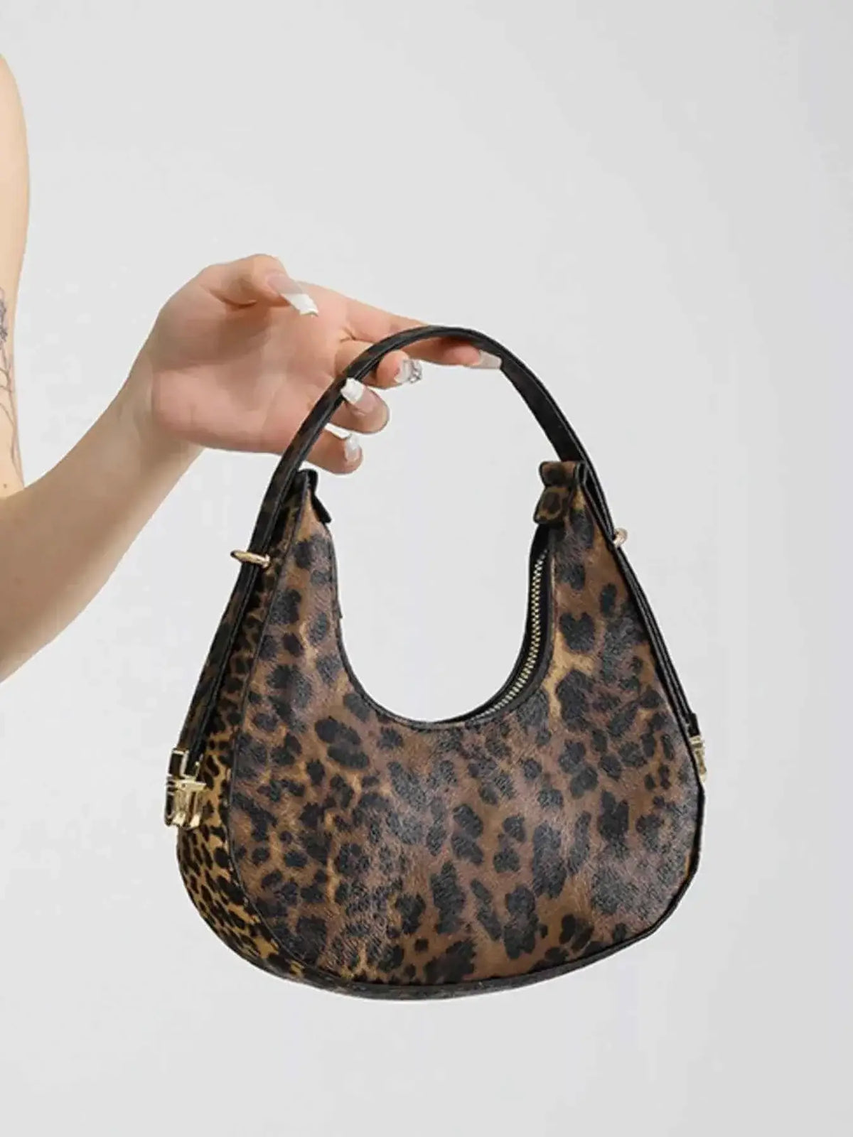 Mini leopard print shoulder bag in PU leather with black handle and gold zipper detailing, featuring a curved shape