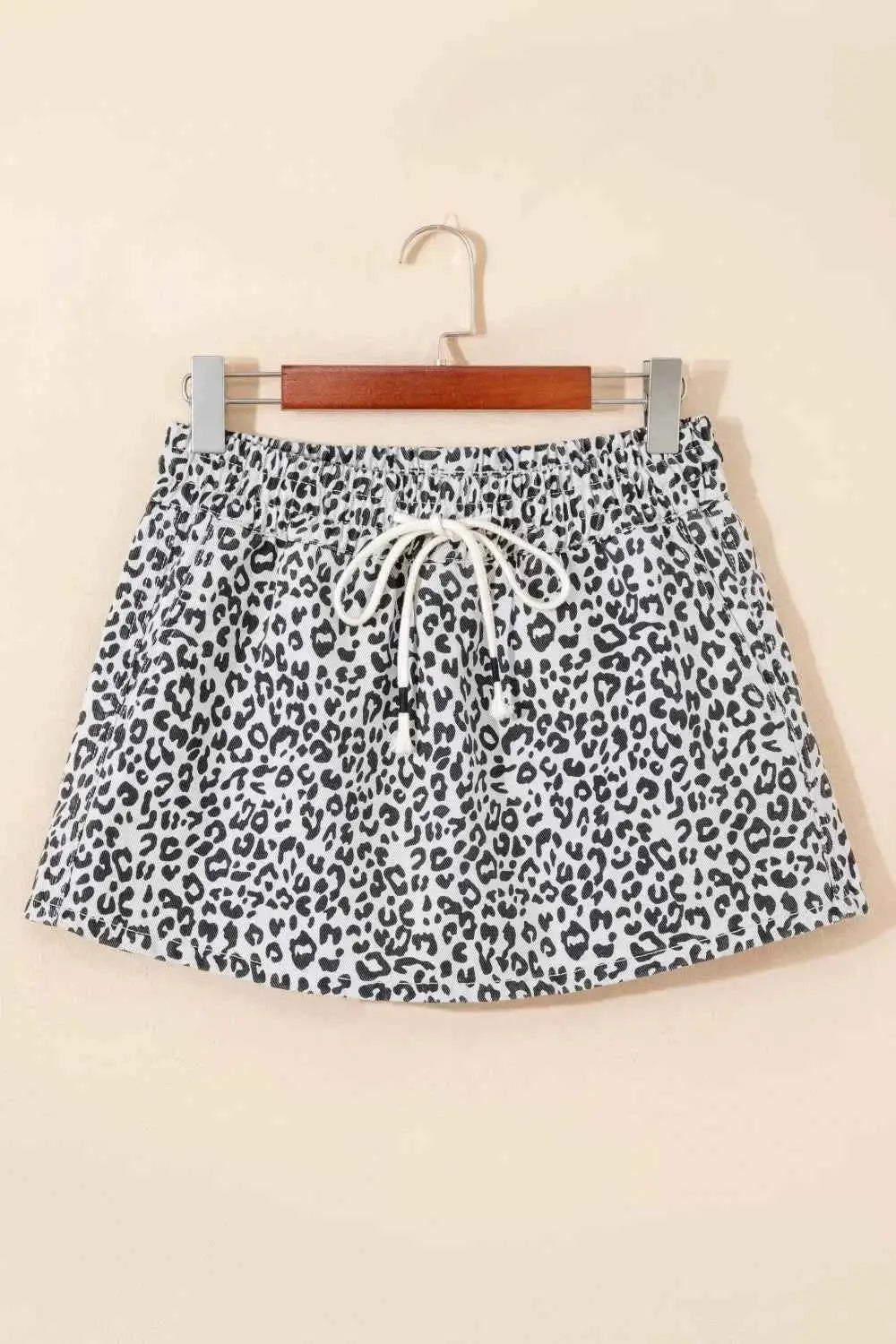Leopard print tassel drawstring casual denim skort in black and white with pockets and a white drawstring on a wooden hanger