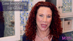 Line Smoothing Lip Gloss applied on lips of a woman with curly red hair and smooth skin wearing a navy top
