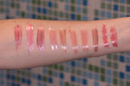 Line Smoothing Lip Gloss swatches on arm in various shades of pink, nude, and peach with glossy finish