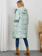 Long Sleeve Longline Hooded Winter Coat in pale green with quilted pattern, pockets, and hooded design, worn with blue jeans and brown boots