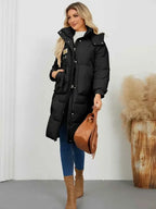 Long Sleeve Longline Hooded Winter Coat in black polyester with pockets and a front zipper closure worn with blue jeans and brown boots