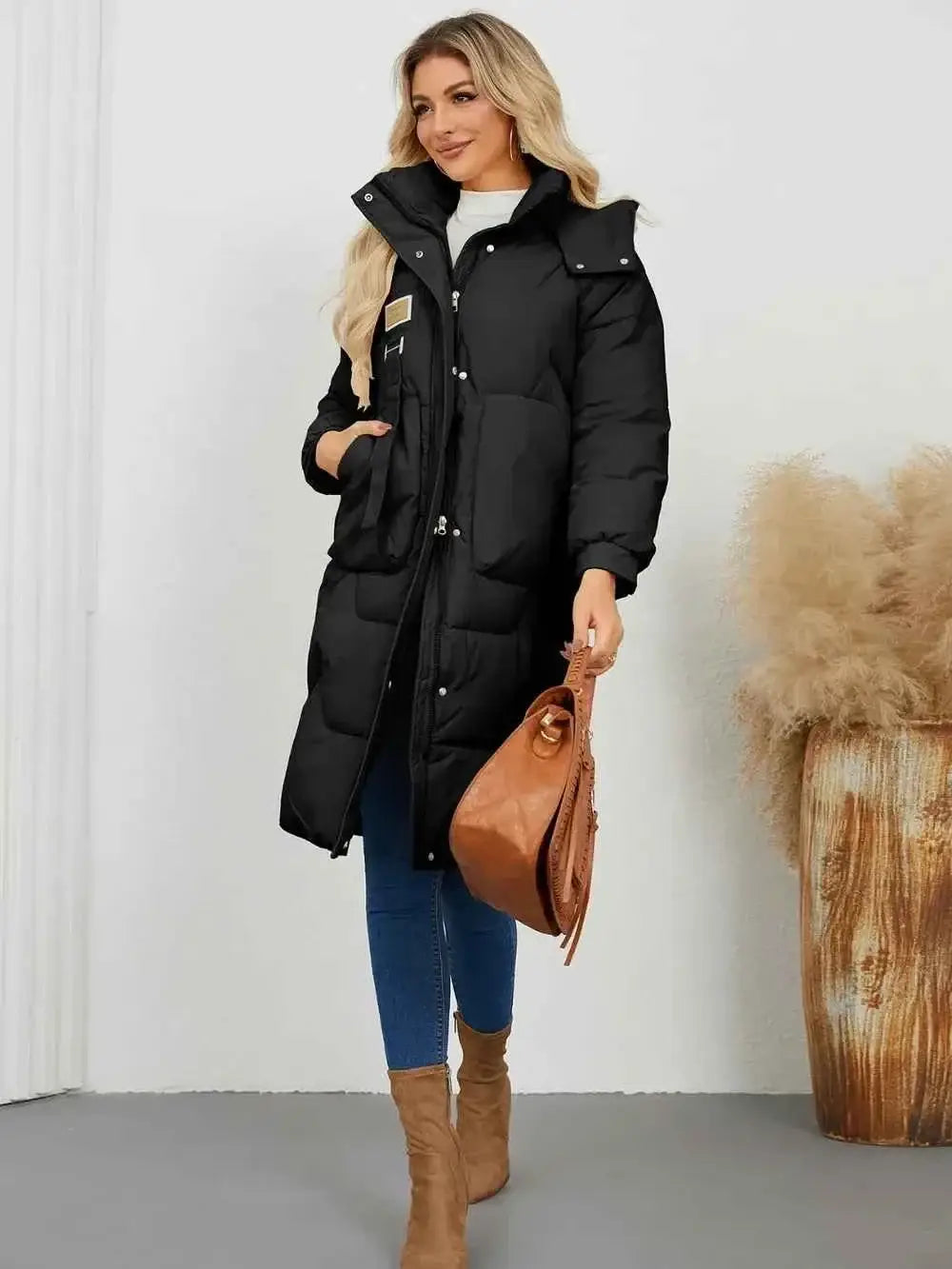 Long Sleeve Longline Hooded Winter Coat in black polyester with pockets and a front zipper closure worn with blue jeans and brown boots
