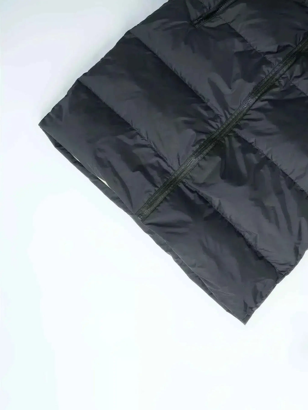 Longline Padded Hooded Vest in black polyester with horizontal padding, visible front zipper and pocketed design