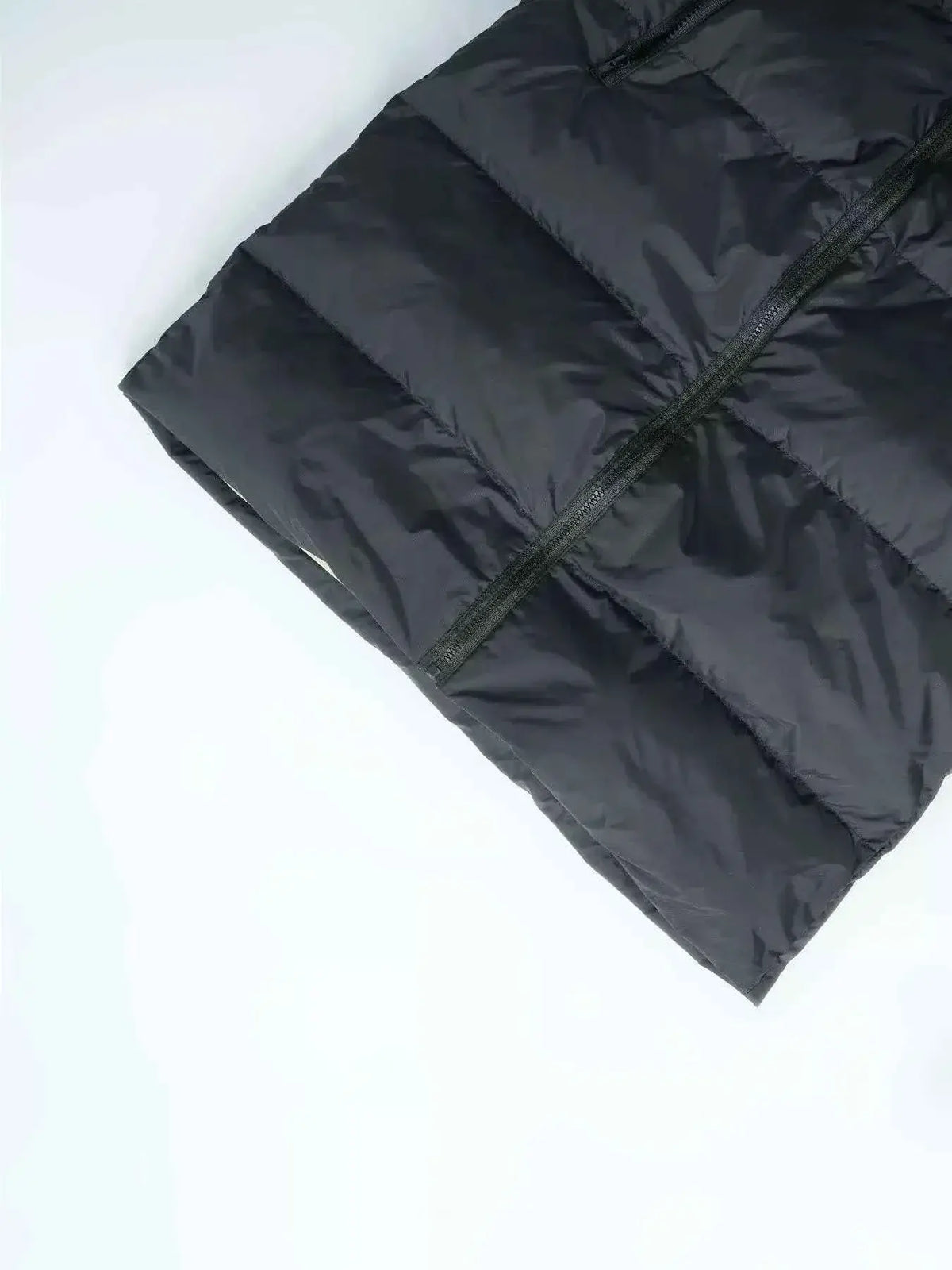 Longline Padded Hooded Vest in black polyester with horizontal padding, visible front zipper and pocketed design