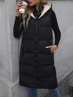 Longline Padded Hooded Vest in black polyester with front zipper, pockets, and cream-colored hood lining worn with black top and jeans