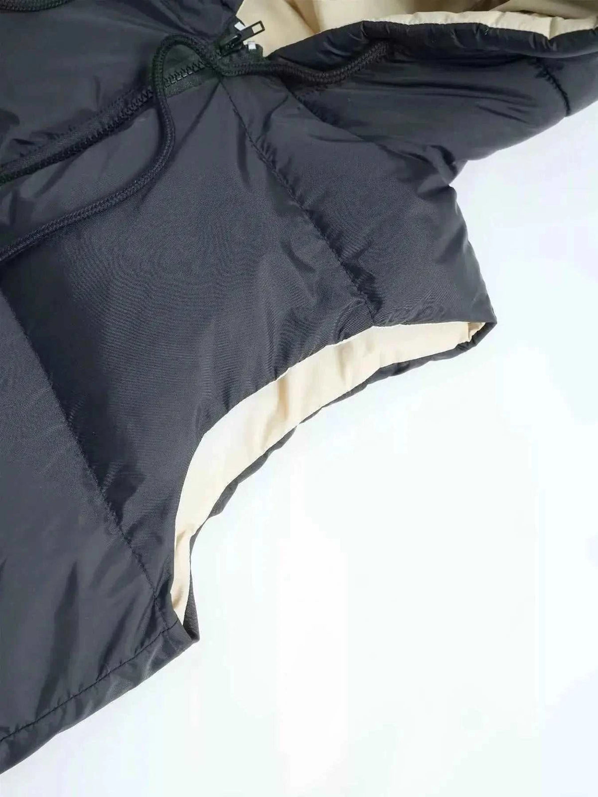 Longline Padded Hooded Vest in black polyester with padded lining and drawstring hood, zipper and pocket details