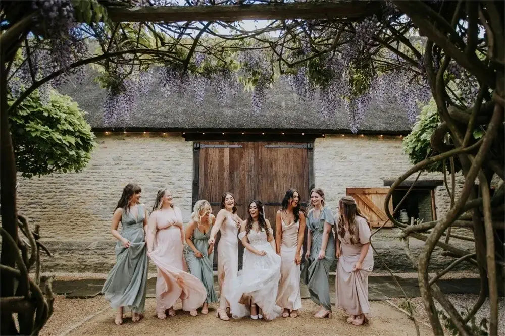 Maternity Mermaid Wedding Dress in white silk satin with strapless neckline and delicate appliques, worn by a bride with bridesmaids in pastel gowns