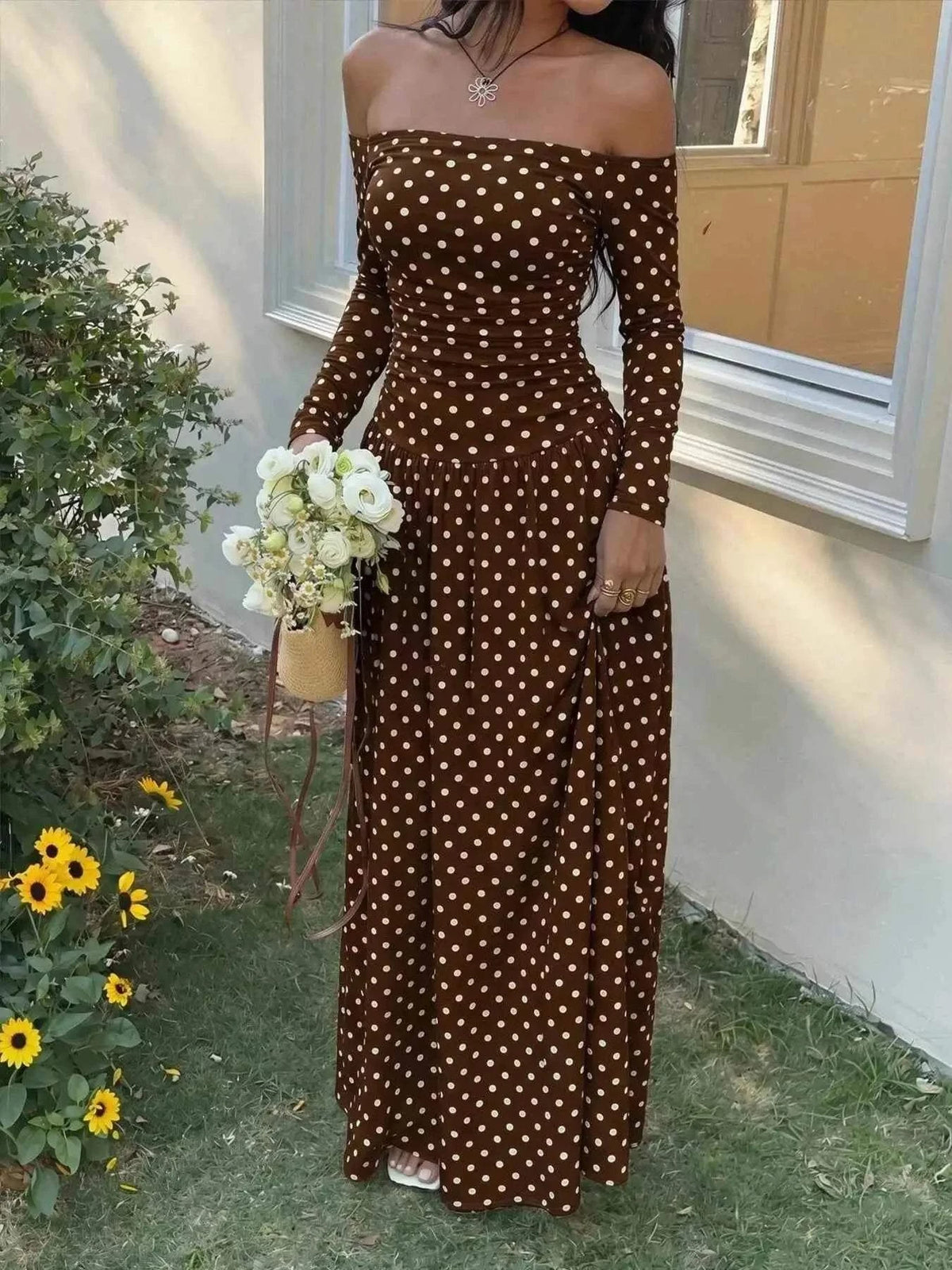 Off-the-Shoulder Maxi Dress in brown with white polka dots, featuring long sleeves and a fitted, flowing silhouette.
