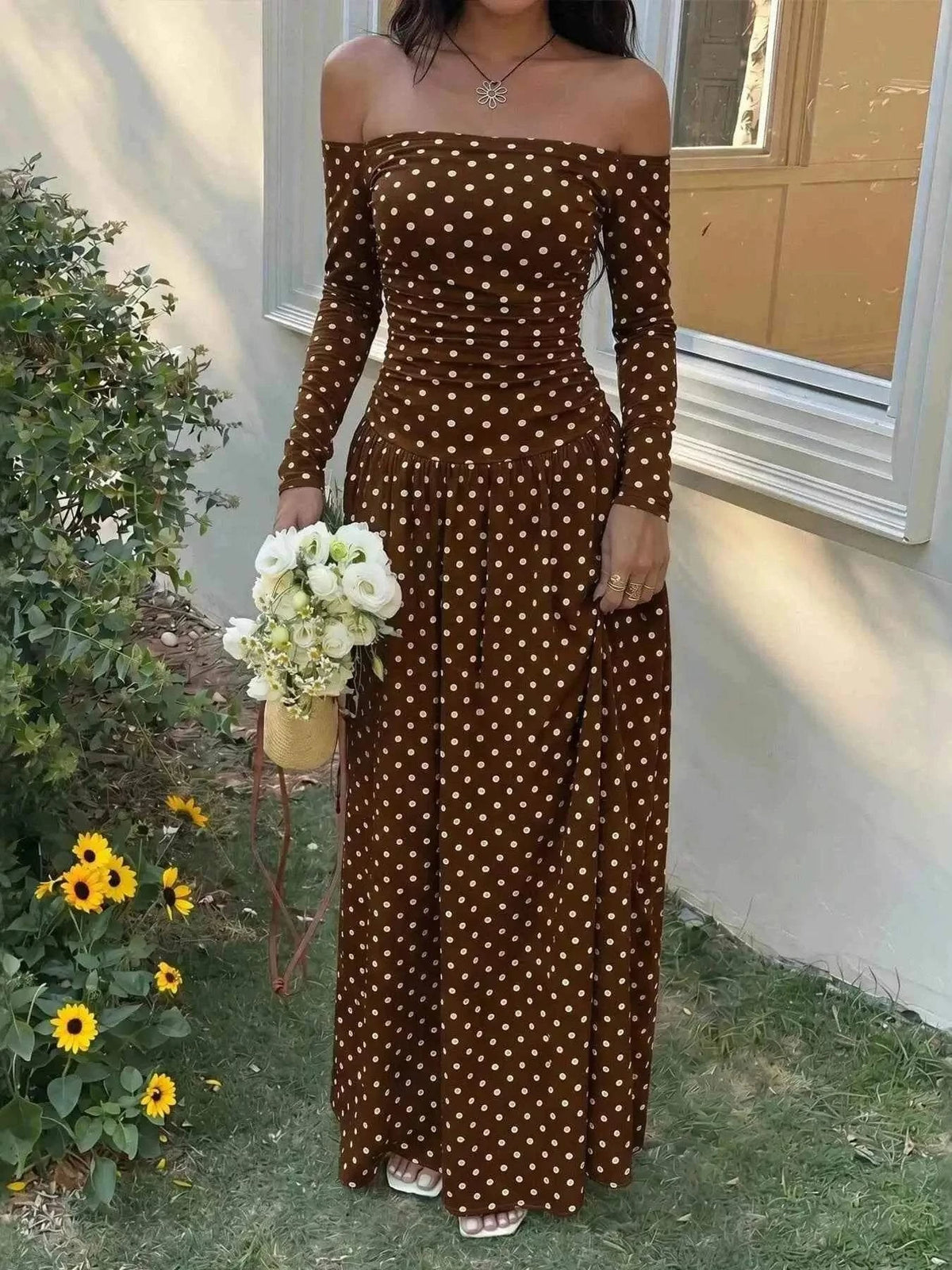 Off-the-Shoulder Maxi Dress in brown fabric with white polka dots, featuring long sleeves and a floor-length flowing skirt.